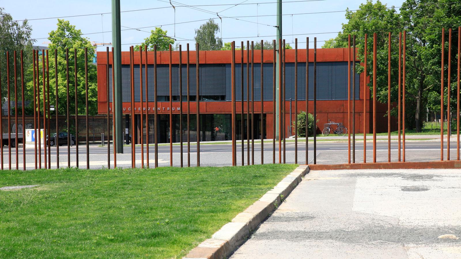 Das Besucherzentrum der Gedenkstätte. Das Foto wurde durch die Stahlstelen der Mauernachzeichnung aufgenommen.