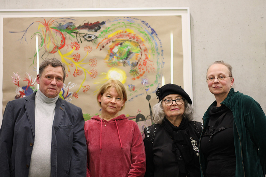 Vier Personen posieren vor einem Gemälde an der Wand