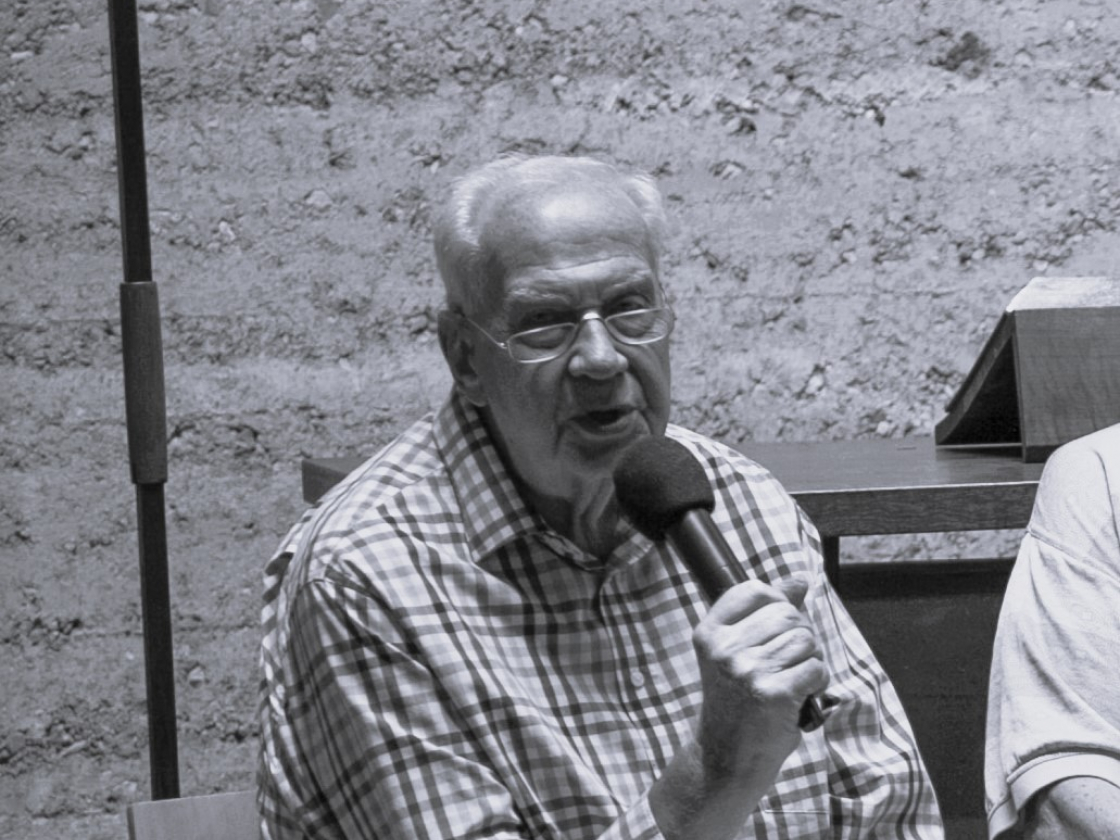 Ralph Kabisch sitzt auf einer Bühne und spricht ins Mikro