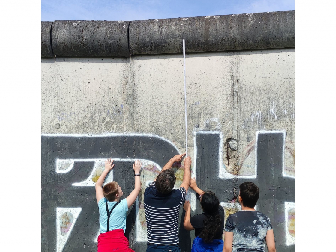 Jugendgruppe misst Höhe der Mauer mit einem Zollstock